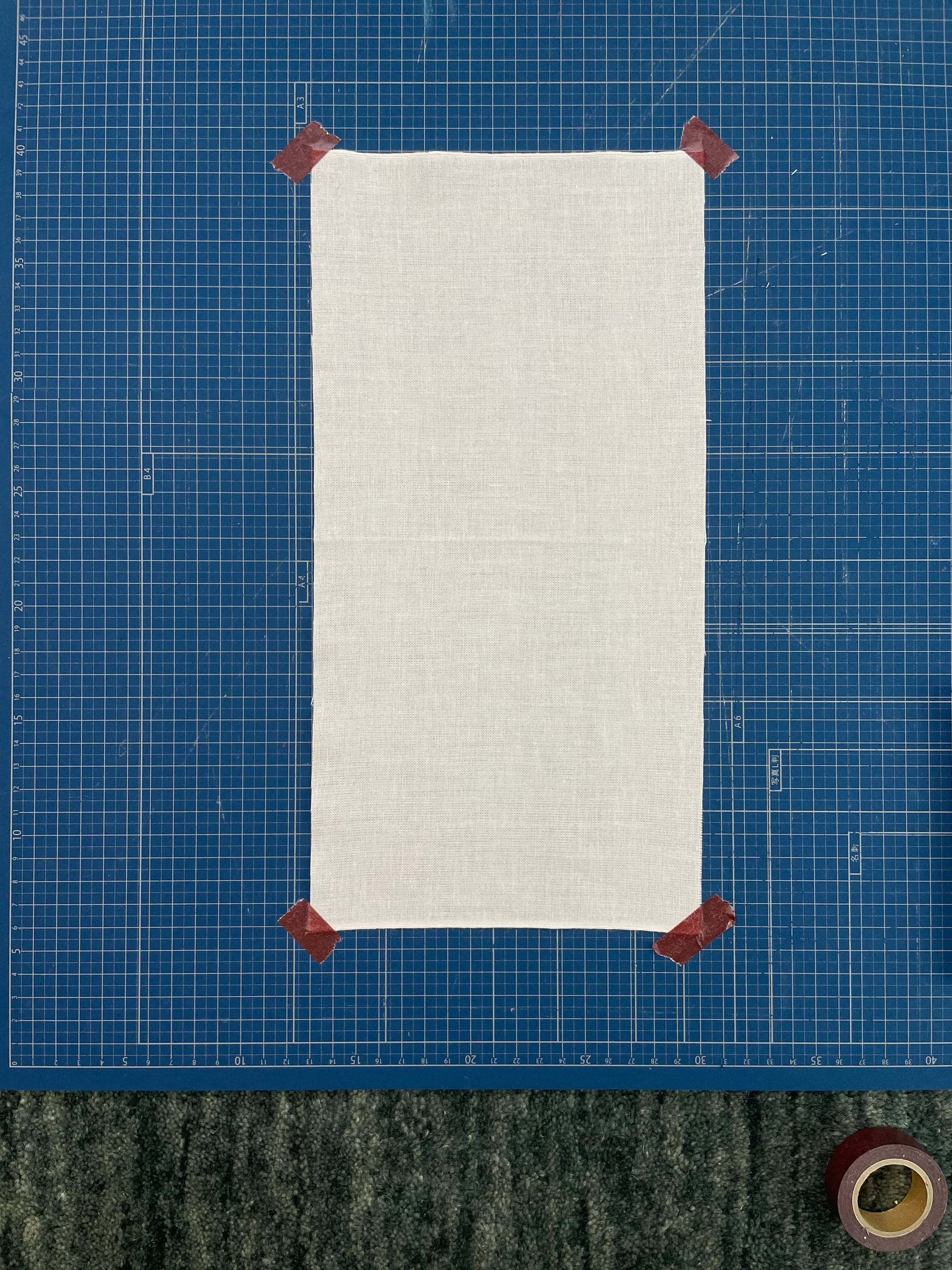 showing a piece of fabric fastened to a cutting mat with washi tape