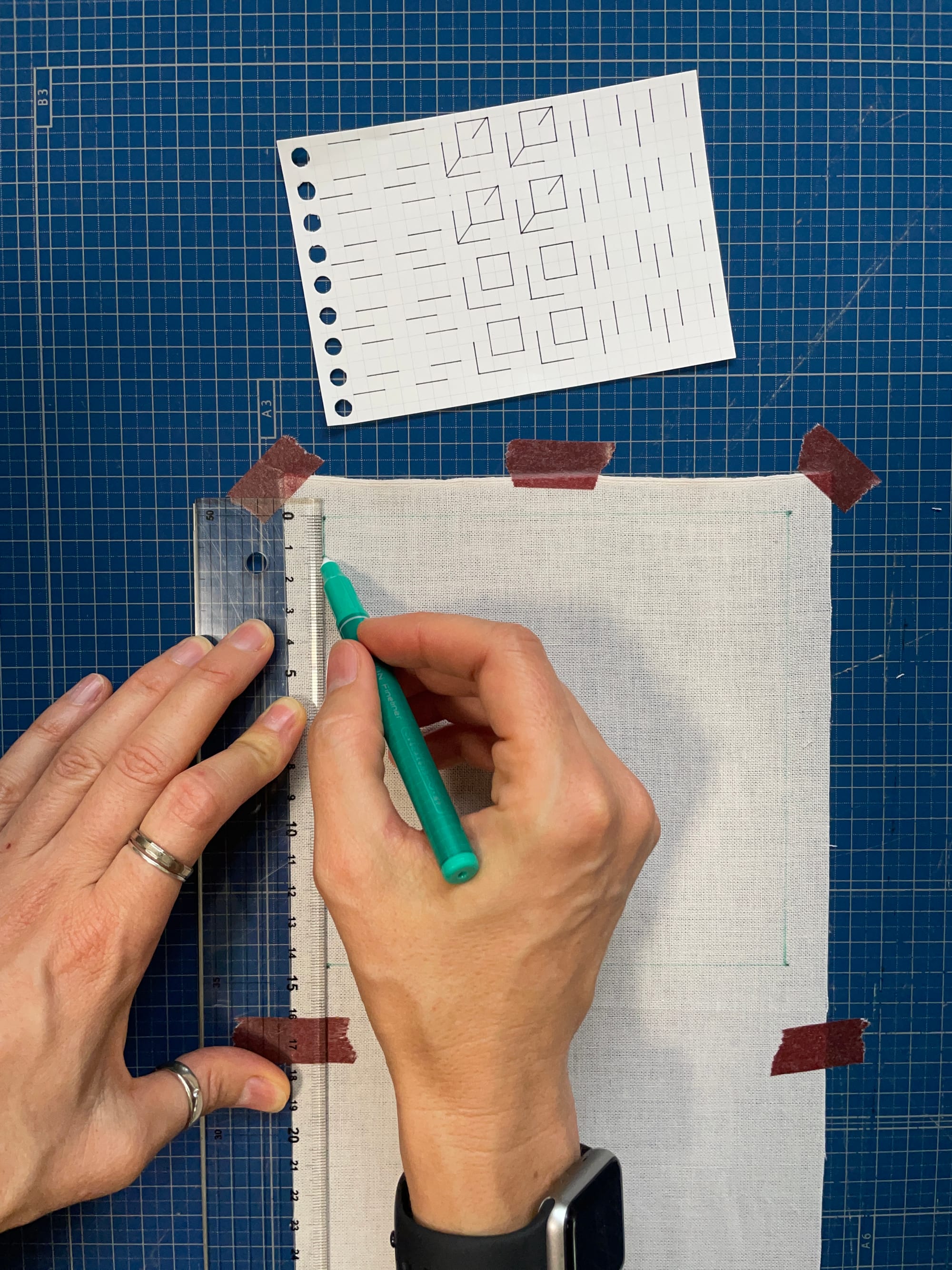 Hands using a ruler to draw a straight line onto fabric