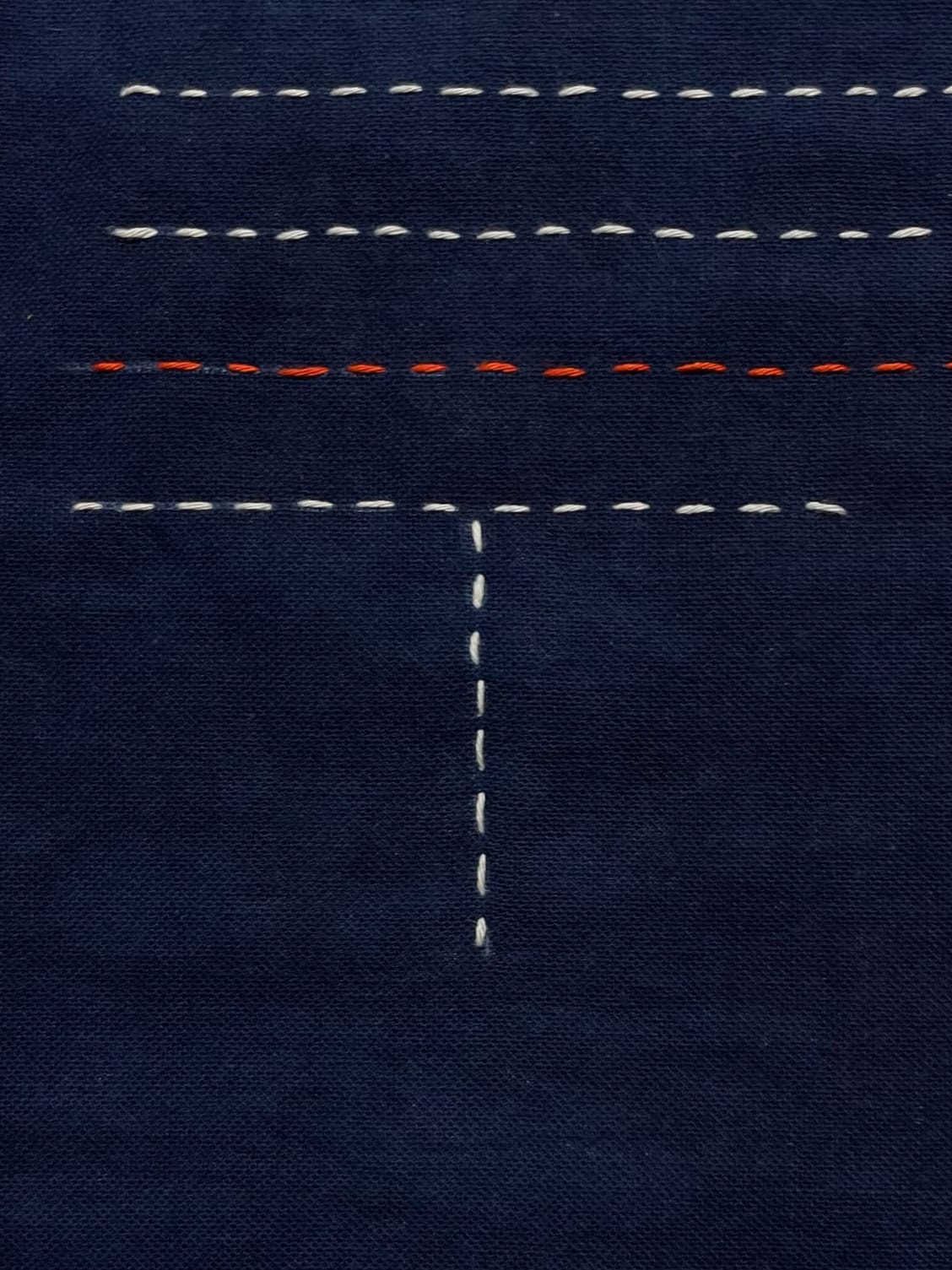 Indigo fabric with white sashiko stitches converging, the point of collision left blank