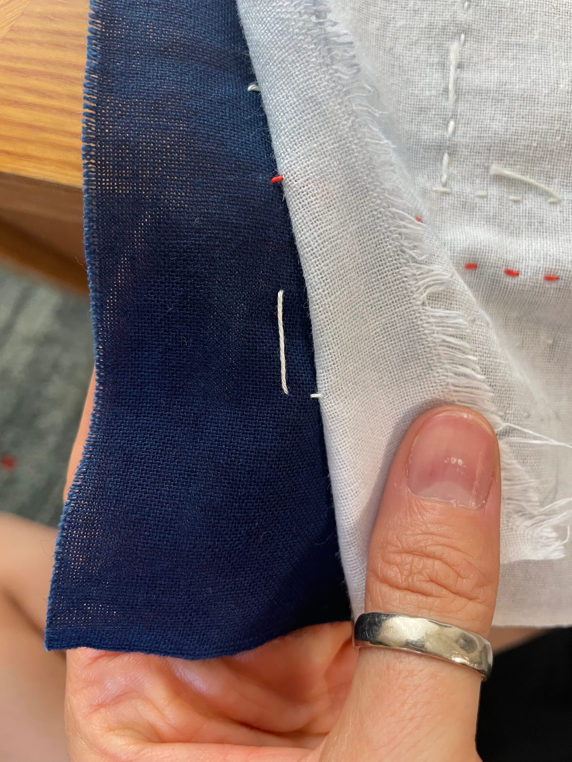 Thread showing in between an indigo and a white piece of fabric to illustrate how to hide carried thread