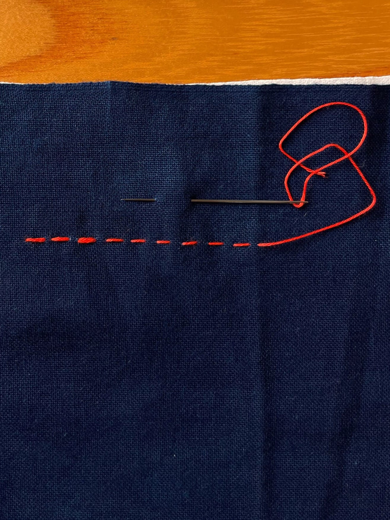 Indigo fabric with nine sashiko stitches in red thread