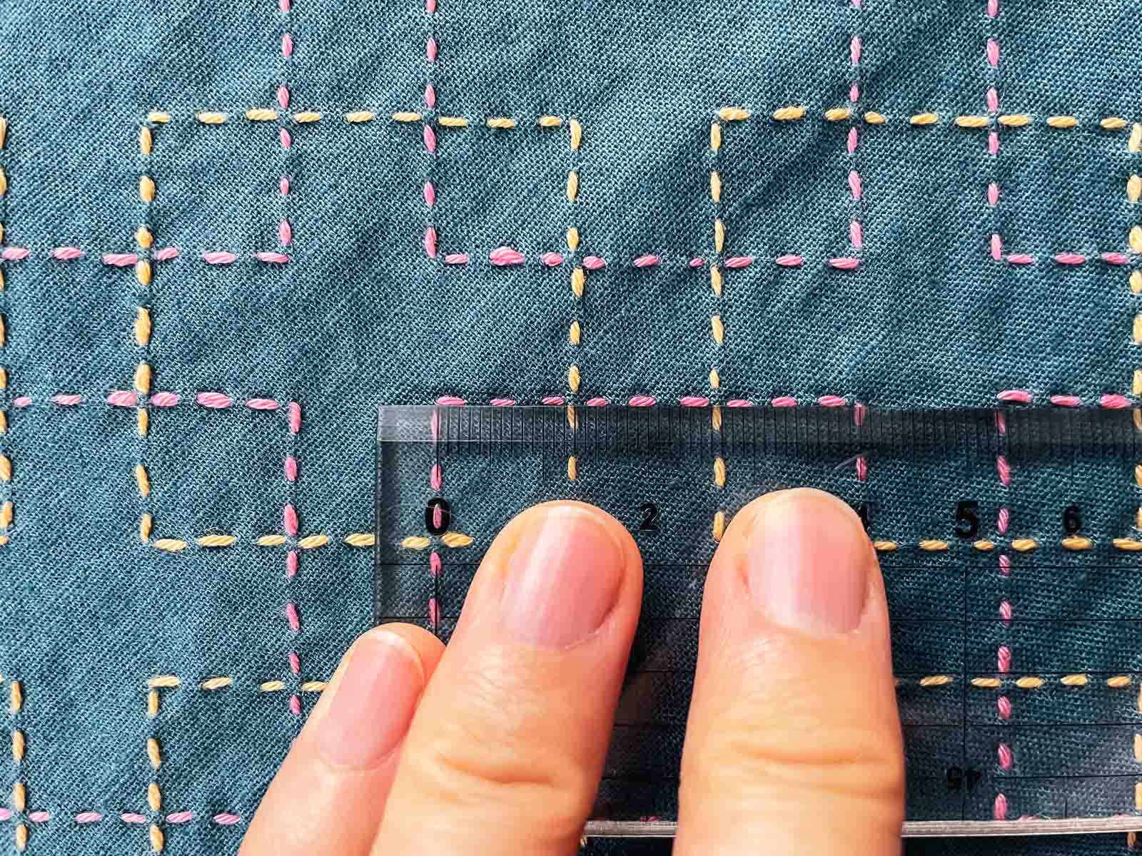 Sashiko cloth with ruler laid on top of moyōsashi to measure stitch length.