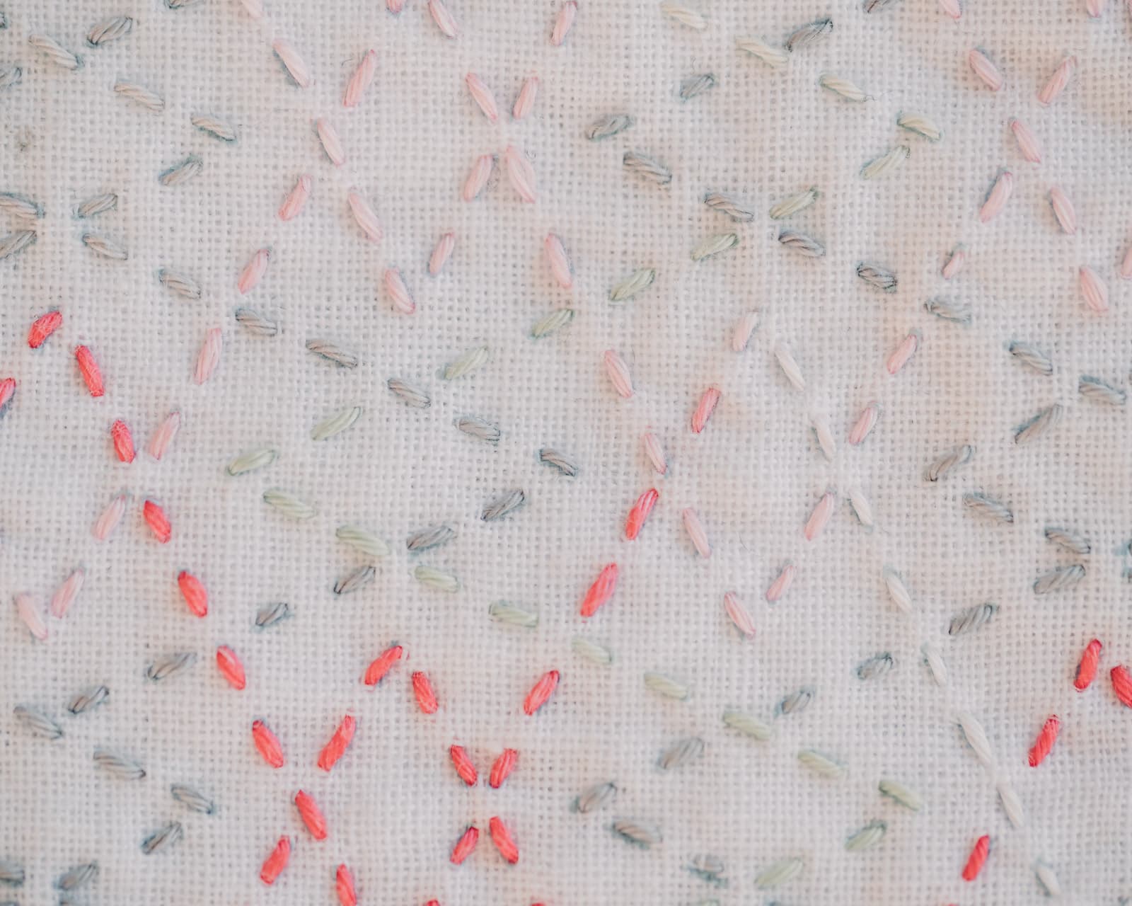 The sashiko pattern tsuzukiyamagata in pastel colors with pink on white fabric up close