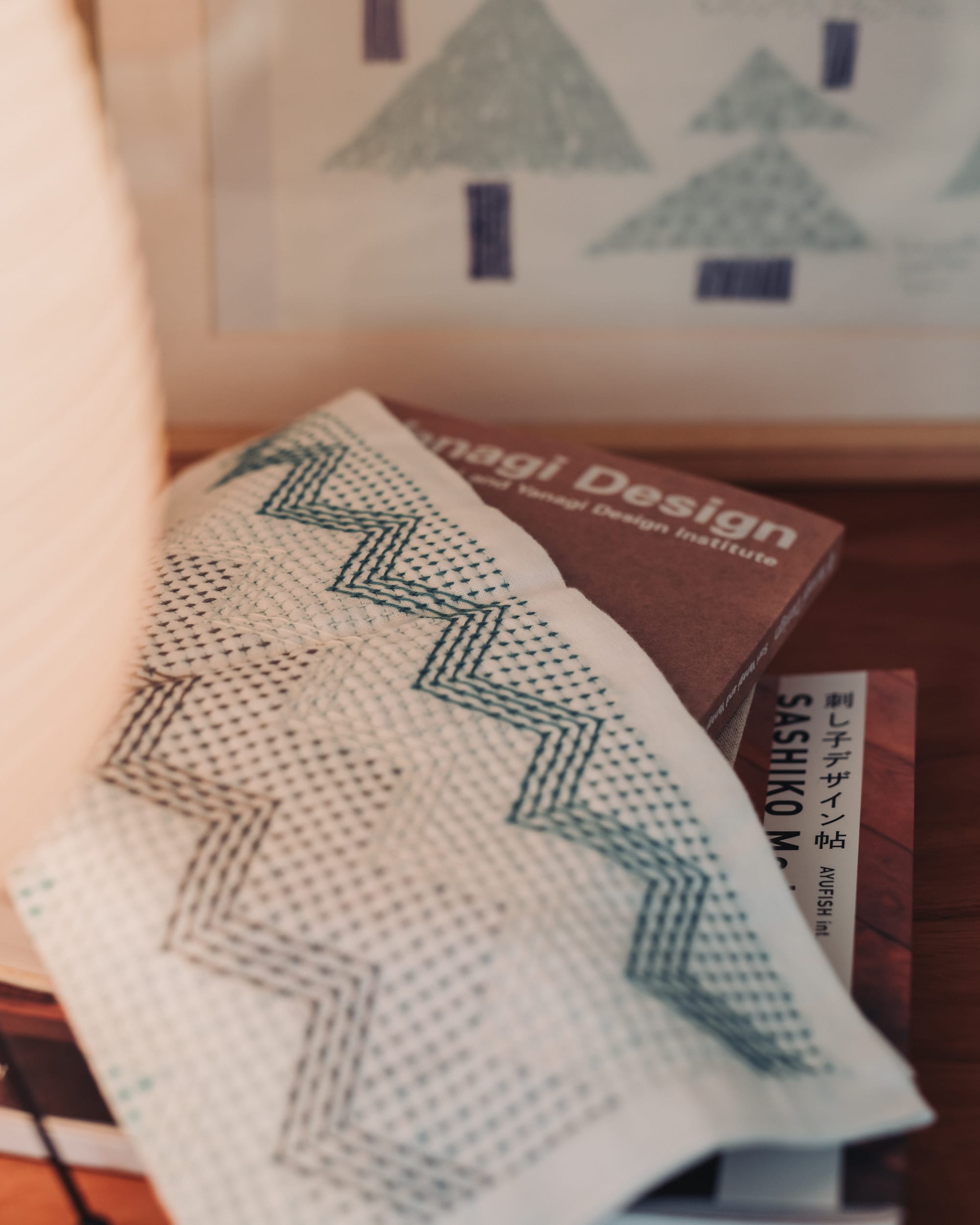 A sashiko kitchen cloth lying on a pile of books, one of them by AYUFISH int.