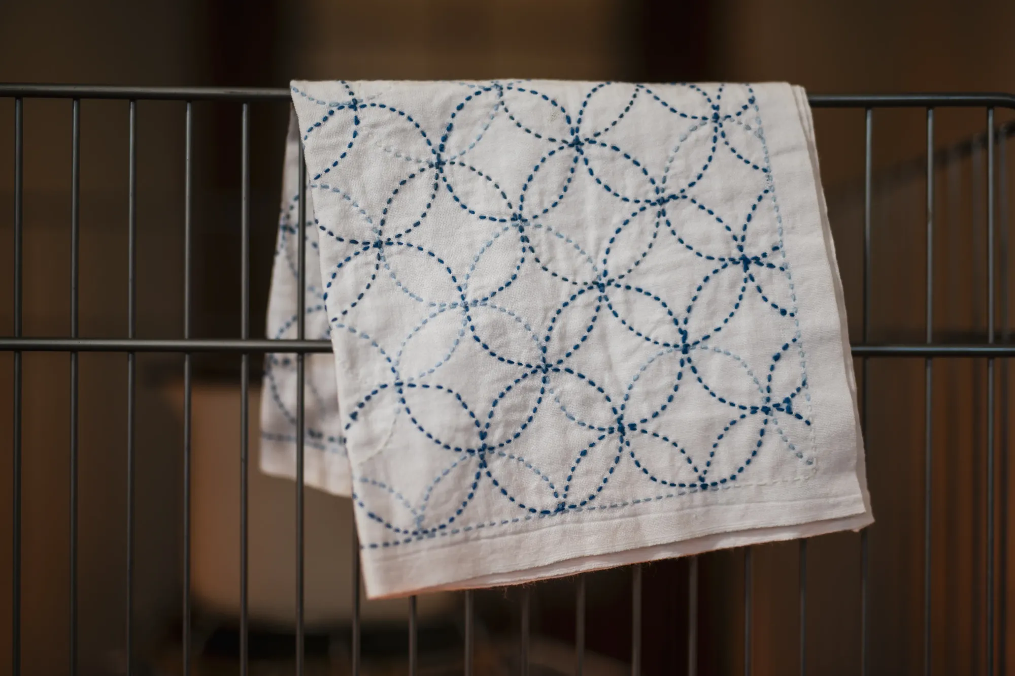 A white sashiko dish cloth with the shippōtsunagi pattern in blue.