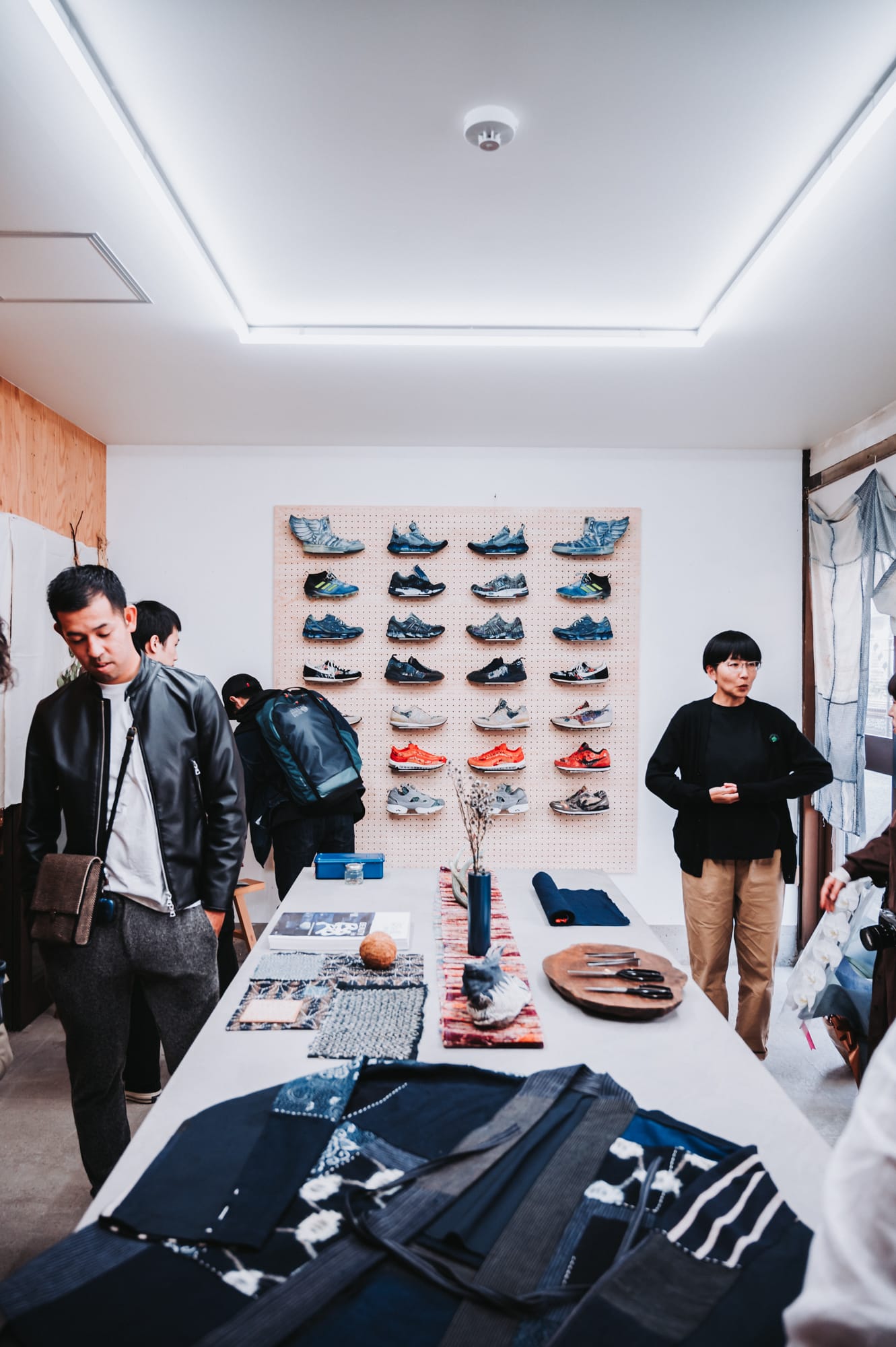 Inside JunAle Sashiko Studio showing a haori and some tools lying on a table and sneakers arranged at a wall