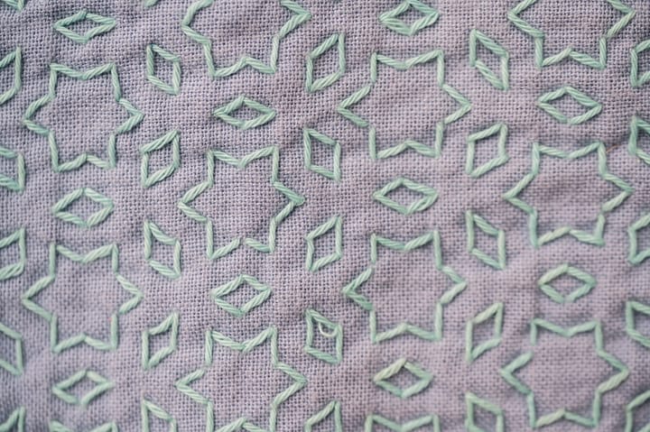 Sashiko pattern "hoshi to mitsubishi" in pale mint green thread on mauve fabric.