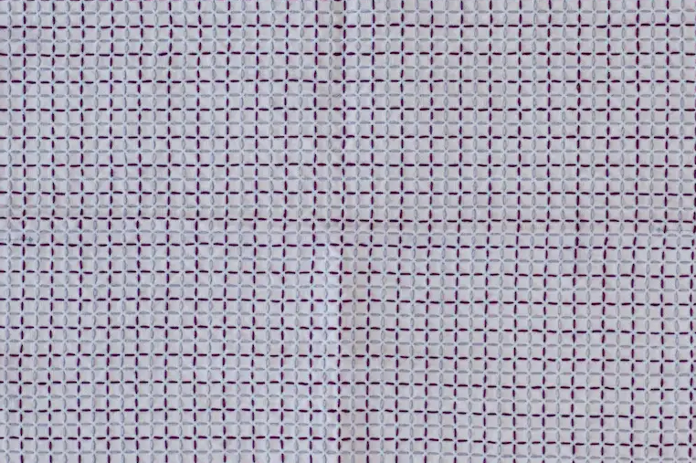 The sashiko pattern kōshi in violet and light blue thread on white fabric.