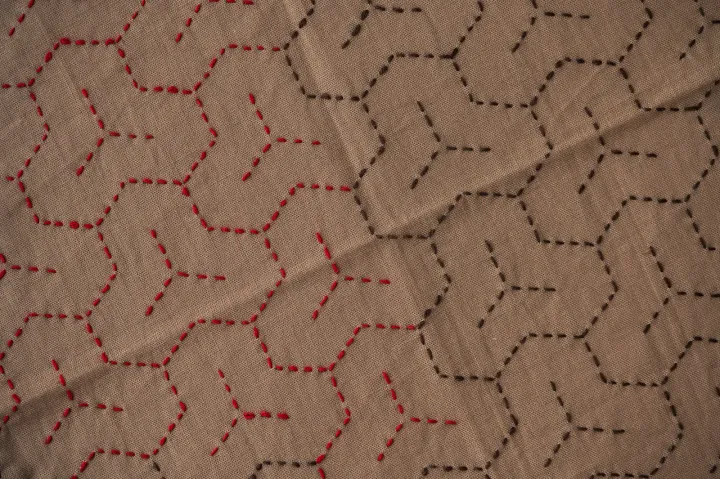 The bishamonkikkō sashiko pattern in brown and red thread on light brown fabric