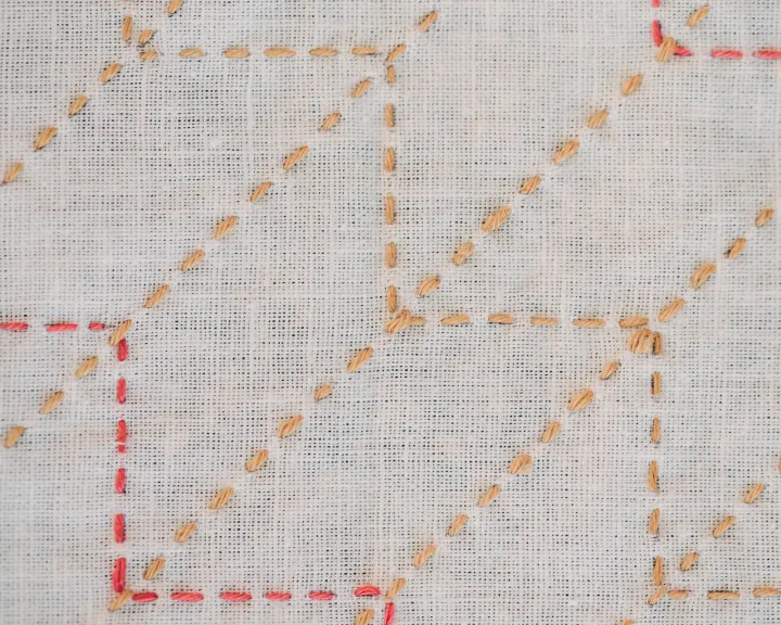 The yabane sashiko pattern in mustard and red thread on white fabric